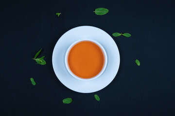 Tomato soup with basil in a bowl. Dark background.