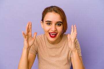 Young arab mixed race woman receiving a pleasant surprise, excited and raising hands.