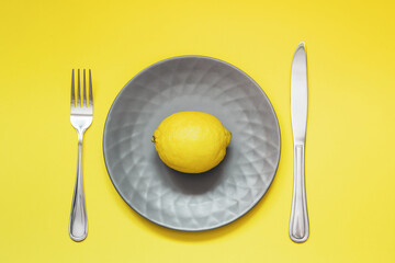 Gray plate with lemon on yellow background. Trending colors 2021 - Ultimate gray and illuminating.