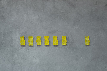 Fototapeta na wymiar Yellow gummy bears on concrete background. Color of the year 2021 - ultimate gray and illuminating.