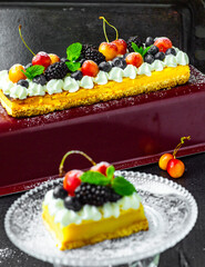 A tasty lemon curd tart with whipped cream and fresh berries on the top. Sour filling on short crust pastry with blackberries, cherries and fresh mint. Vertical orientation.