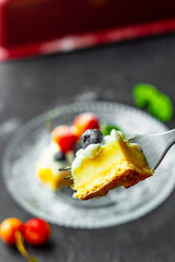 A blueberry on a piece of tasty lemon curd tart with whipped cream and fresh berries on the top. Close up. Vertical orientation.