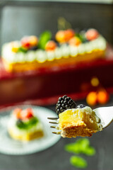 A blackberry on a piece of tasty lemon curd tart with whipped cream and fresh berries on the top. Close up. Vertical orientation.