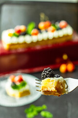 A sugar powdered blackberry on a piece of tasty lemon curd tart with whipped cream and fresh berries on the top. Close up. Vertical orientation.