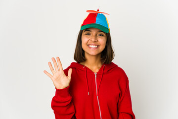 Young hispanic woman wearing a cap with propeller isolated smiling cheerful showing number five with fingers.