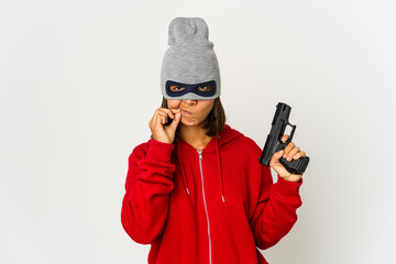 Young robber hispanic woman wearing a mask with fingers on lips keeping a secret.
