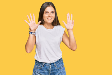 Young caucasian woman wearing casual white tshirt showing and pointing up with fingers number nine...