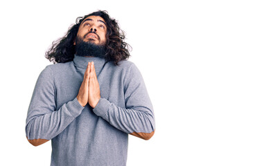 Young arab man wearing casual clothes begging and praying with hands together with hope expression on face very emotional and worried. begging.