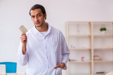 Young male doctor suggesting pills in the clinic