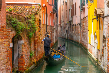 Venetian gondolier punting gondola through green canal waters of Venice Italy © Pawel Pajor