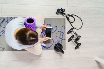Top view on young caucasian woman sitting on the floor at home watching online video for training - Girl with digital tablet looking for workout on internet - health and fitness concept copy space