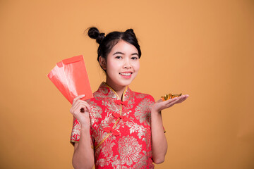 Beautiful woman wearing cheongsam and smiling at you in chinese new year on yellow background