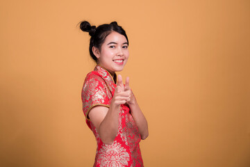 Beautiful woman wearing cheongsam and smiling at you in chinese new year on yellow background