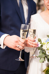 Bride and groom are holding wedding glasses with champagne. Wedding ring. Wedding ceremony. Newlyweds.