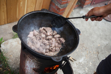 Roasting meat in a cauldron. Open fire.