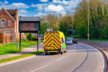 Traffic information sign in England during Covid 19 pandemic with  passing by blurry ambulance