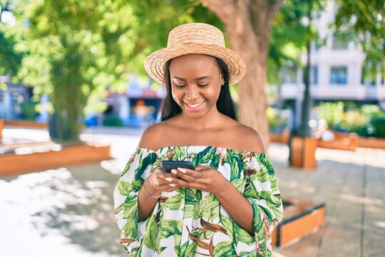 Young african american tourist woman on vacation smiling happy using smartphone at the city.