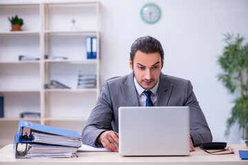 Young male employee unhappy with excessive work in the office