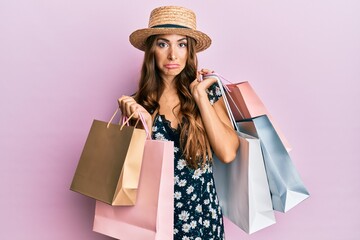 Young brunette woman holding shopping bags depressed and worry for distress, crying angry and afraid. sad expression.