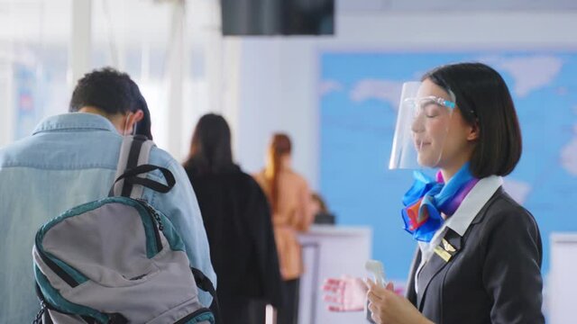 Caucasian female airline staff measuring body temperature of passenger