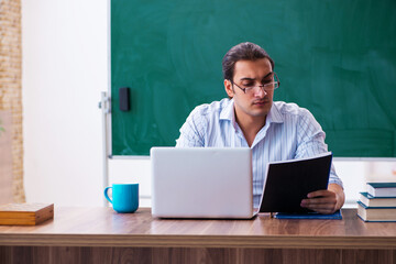 Young male teacher in front of blackboard