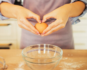 young woman in a gray aprons breaks the eggs