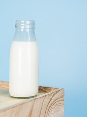 Bottle milk for a drink on a wooden crate box..fresh milk and glass on a blue background..Milk consumption nutritious and healthy dairy products concept.