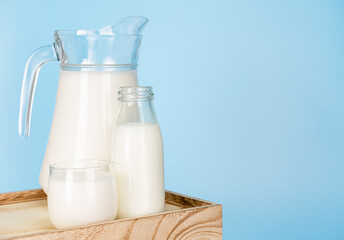 Bottle milk for a drink on a wooden crate box..Jug of fresh milk and glass on a blue background..Milk consumption nutritious and healthy dairy products concept.