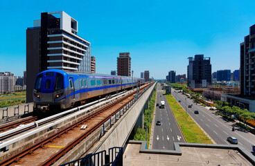 Fototapeta na wymiar Scenic view of a metro train traveling on the elevated rails of Taoyuan Mass Rapid Transit System by residential towers under blue sunny sky in Chunli, Taoyuan, Taiwan 