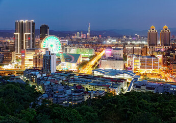 Fototapeta premium Aerial panorama of busy Taipei City, the capital of Taiwan, with view of a giant Ferris wheel in Dazhi Commercial District & Taipei 101 Tower in downtown area at dusk ~ A romantic night in Taipei