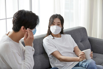 마스크를 쓰고 소파에서 시간을 보내는 커플