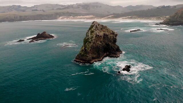 Spectacular nature aerial around rock formation reveal Sandfly Bay, Otago Peninsula.  Cold cloudy morning