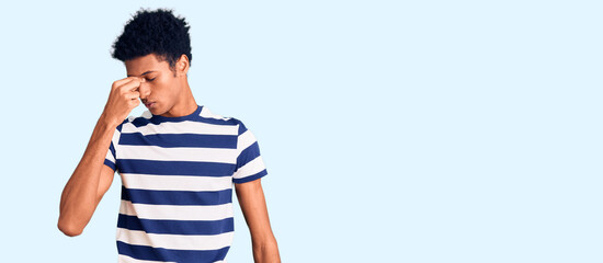 Young african american man wearing casual clothes tired rubbing nose and eyes feeling fatigue and headache. stress and frustration concept.