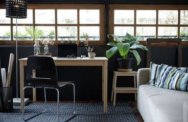 Modern home office creative space perfect for working from home lifestyle with laptop on the desk and sofa in the living room, Quarantine isolation during the Coronavirus (COVID-19) health crisis