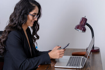 Mujer de negocios trabajando en casa y enviando mensajes con su celular. Concepto de mujer latina...