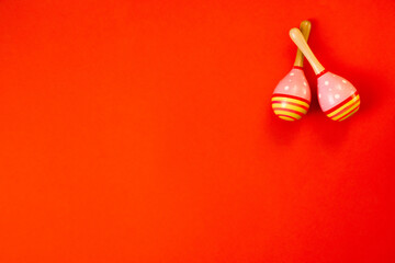 Top view colored maracas on bright orange background. Left place for text. Traditional carnival. Celebration of Cinco de Mayo. Left copy space