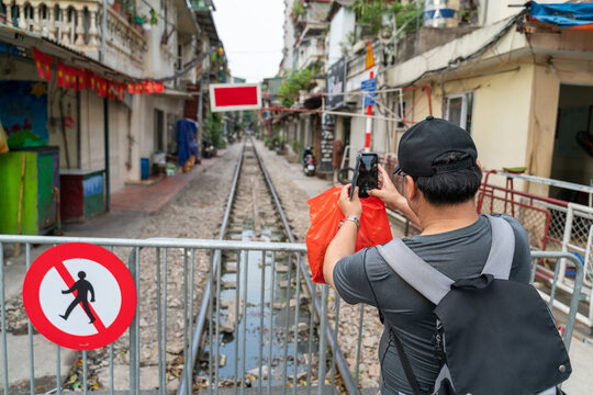 Male tourist taking photo of Hanoi railway next to the "don't walk" sign