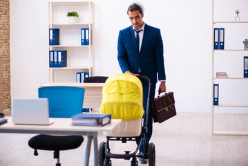 Young male employee looking after kid at workplace