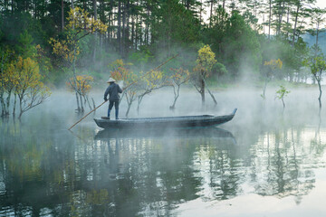 Obraz na płótnie Canvas Fisher man with wooden boat at Tuyen Lam lake, Da Lat, Vietnam