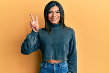 Young latin transsexual transgender woman wearing casual clothes smiling with happy face winking at the camera doing victory sign. number two.