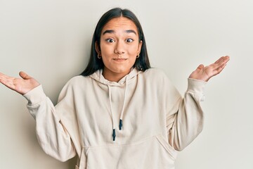 Fototapeta premium Young asian woman wearing casual sweatshirt clueless and confused with open arms, no idea and doubtful face.