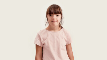 Portrait of disabled girl with Down syndrome smiling at camera while posing isolated over white...