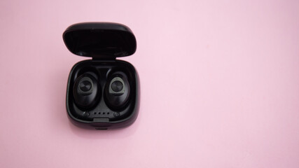 Top view of wireless earbud in case isolated on pink