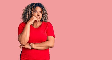 Young african american plus size woman wearing casual clothes serious face thinking about question with hand on chin, thoughtful about confusing idea