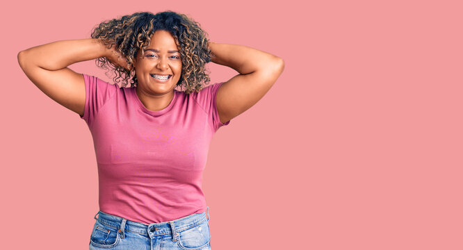 Young african american plus size woman wearing casual clothes relaxing and stretching, arms and hands behind head and neck smiling happy