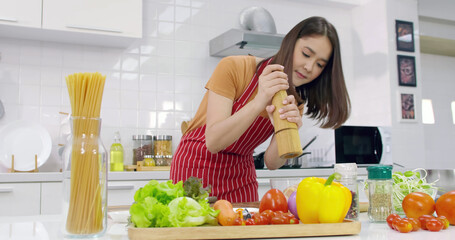 Young Asian woman cooking in kitchen at home.