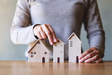 Closeup image of a woman holding wooden house models on the table