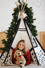 Girl in red plaid shirt in Christmas wigwam © olgasparrow