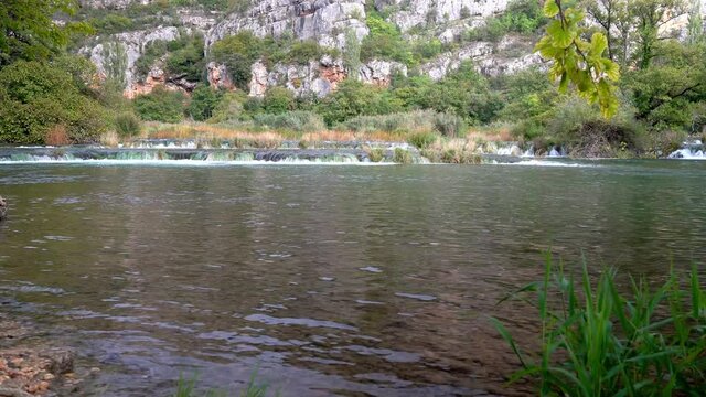 Short but wide and strong waterfalls from one pond to another submerging grass in Krka National Park in Croatia in fall