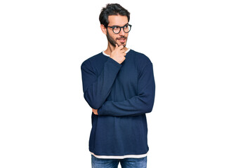 Young hispanic man wearing casual clothes and glasses with hand on chin thinking about question, pensive expression. smiling with thoughtful face. doubt concept.